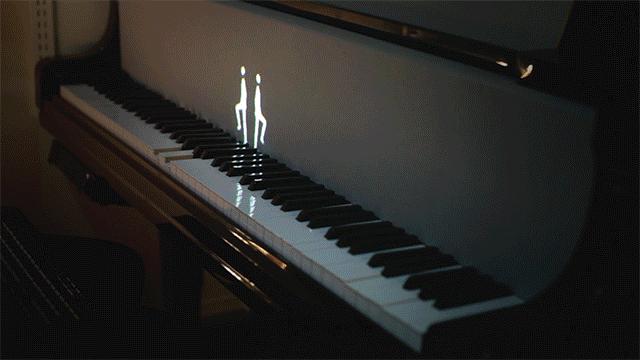 projected figures of humans and animals play the keyboard through medium