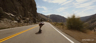 skateboarder zips down mountains and flies by cars at small